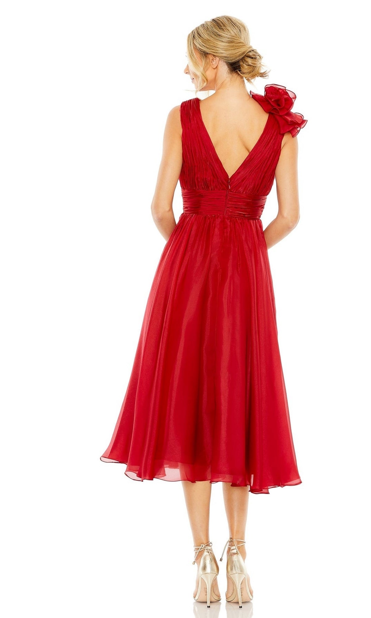 A woman stands facing away in high heels, wearing the Mac Duggal 49494 Short Ruched Wedding-Guest Dress—a sleeveless, knee-length red dress with a V-back and one-shoulder ruffle detail.